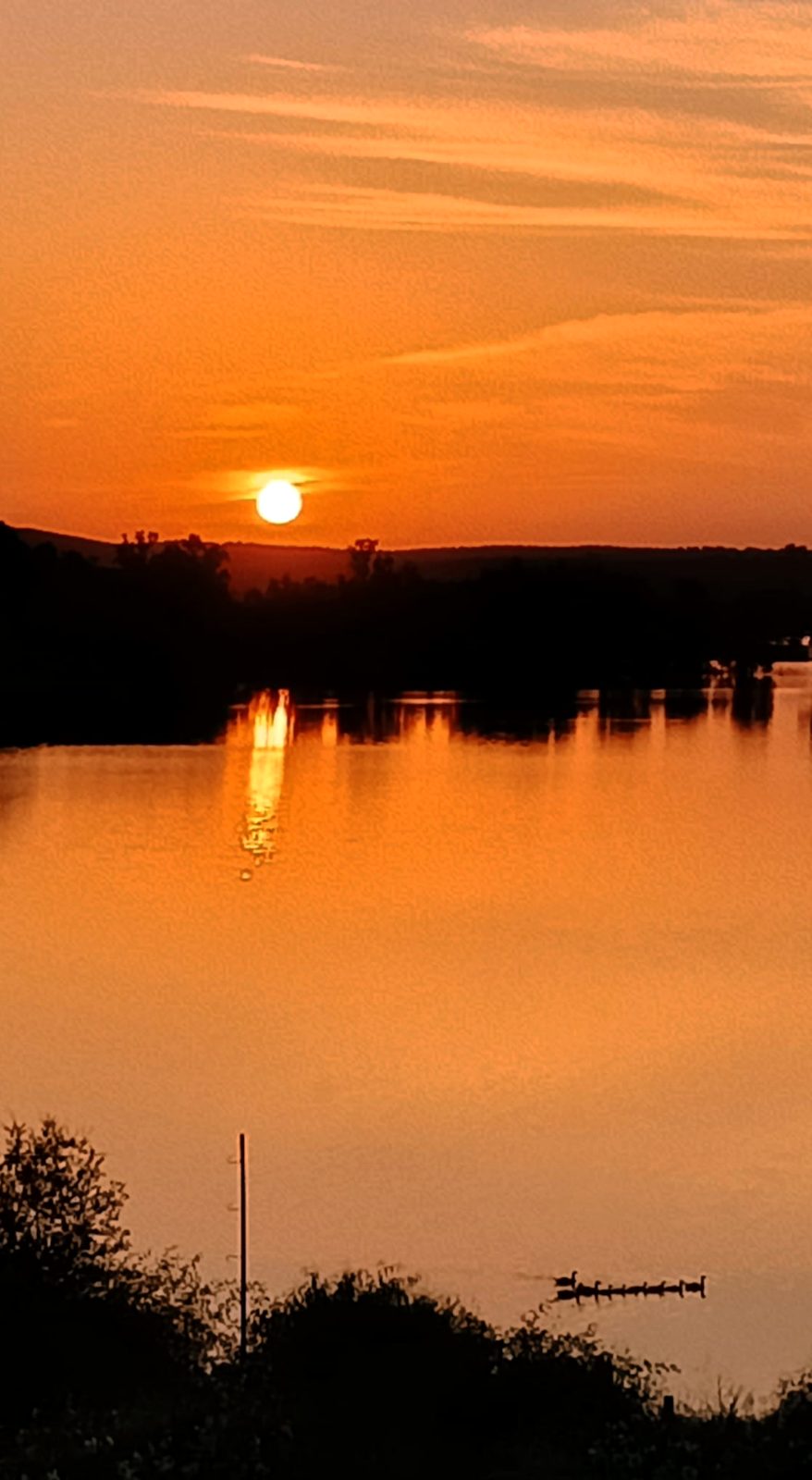 Atardecer anaranjado reflejado en el lago
