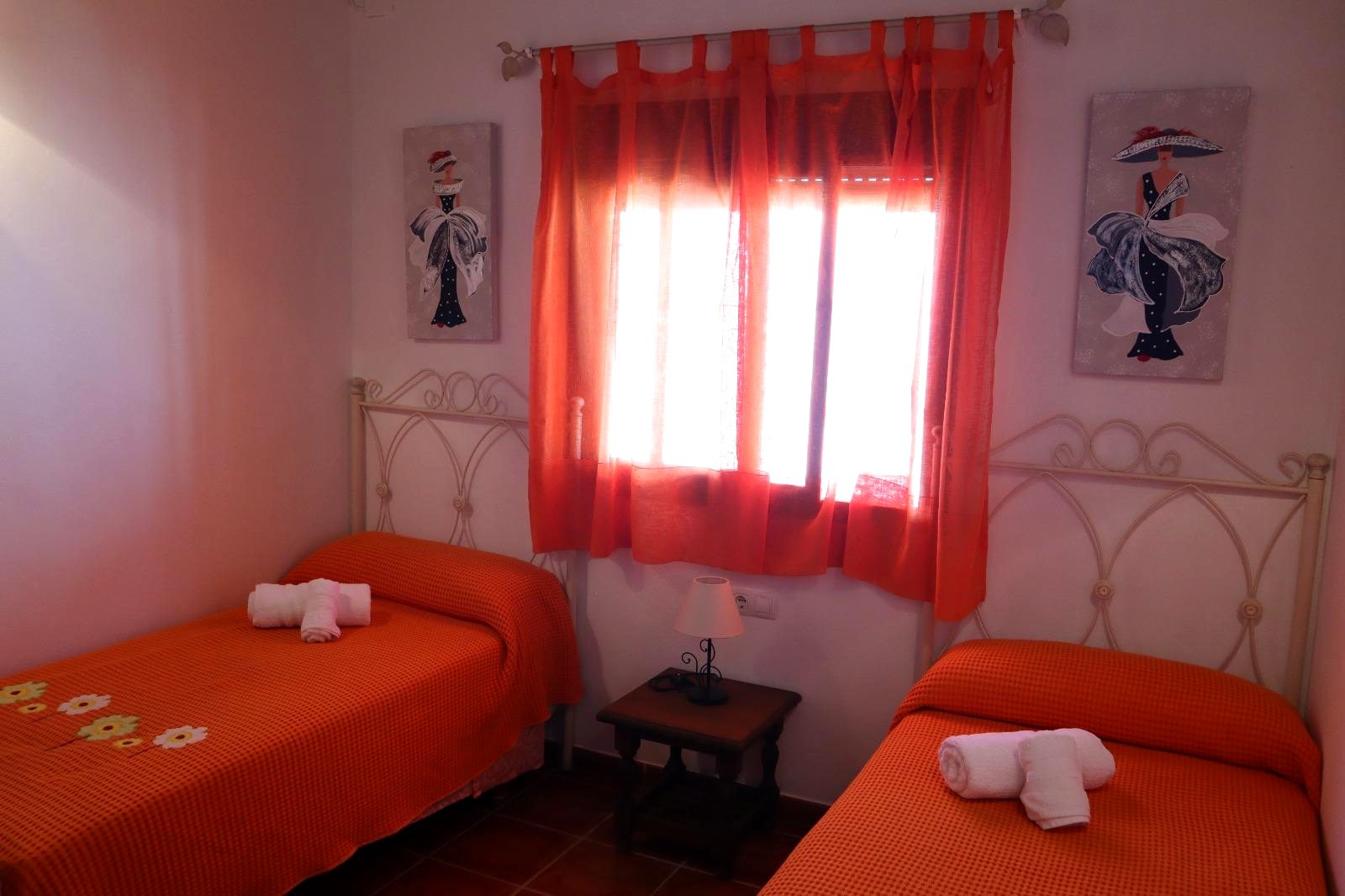 Dormitorio con dos camas individuales y colchas naranjas