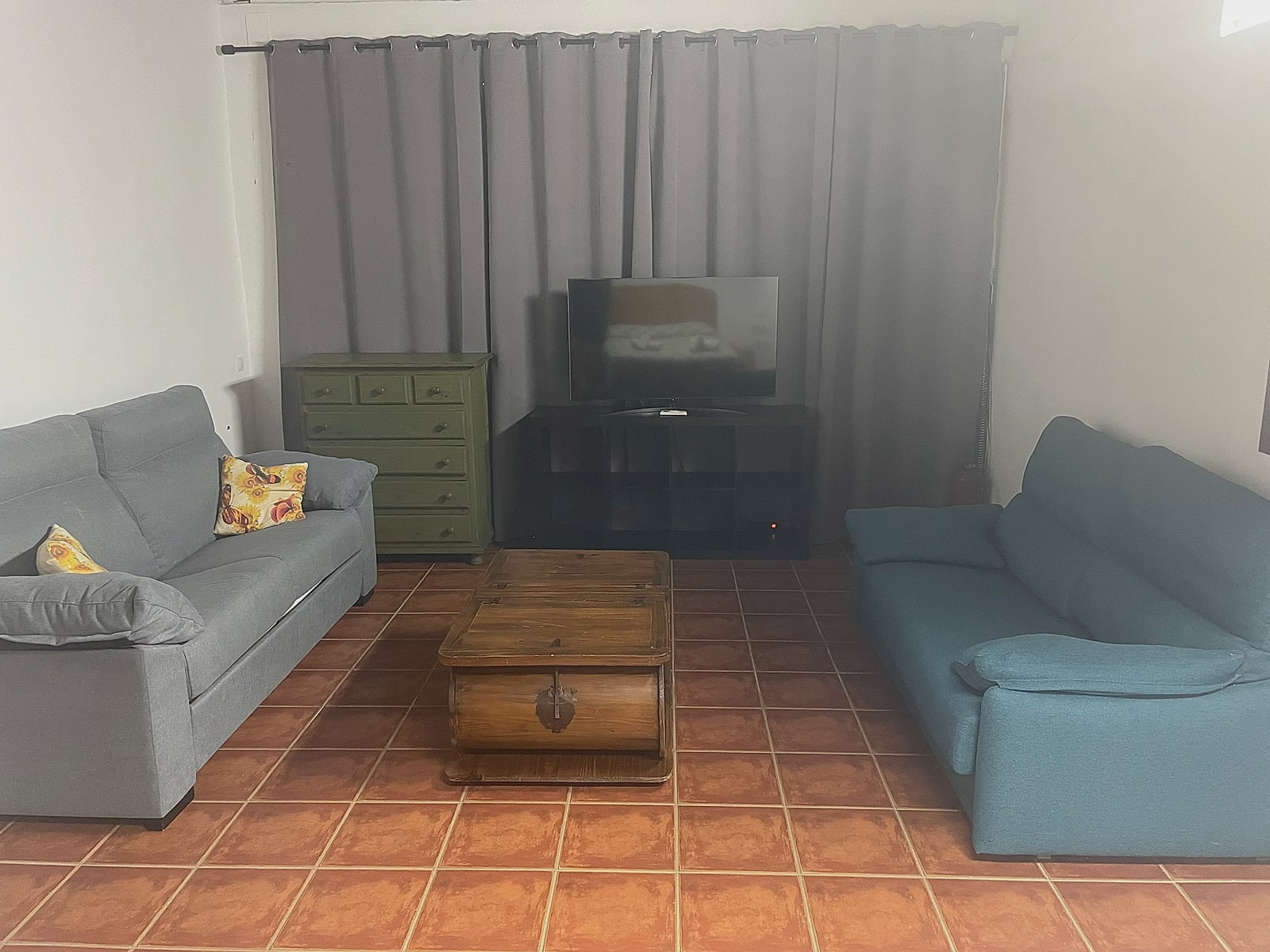 Zona de estar del cuarto con dos sofás, cómoda y televisión