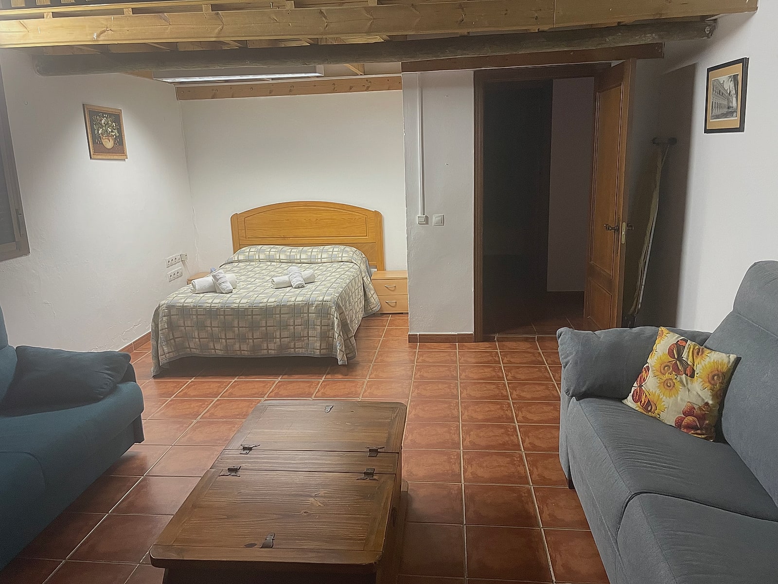 Cama de matrimonio del cuarto, bajo el altillo con vigas de madera